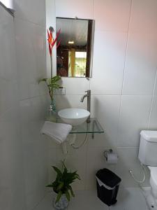 a white bathroom with a sink and a mirror at Suíte Solar in Ilha do Mel