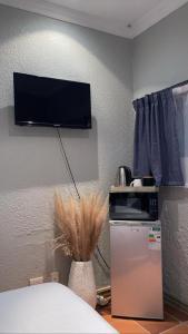 a room with a tv on the wall and a refrigerator at OR Tambo Stay Unit 2 in Boksburg