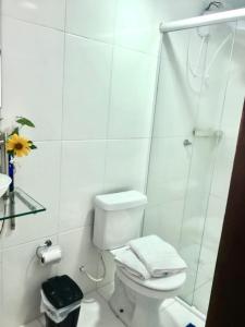 a white bathroom with a toilet and a shower at Suíte Solar in Ilha do Mel