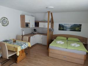 a bedroom with a bed and a table and a kitchen at Apartmaji Vesna in Bohinj