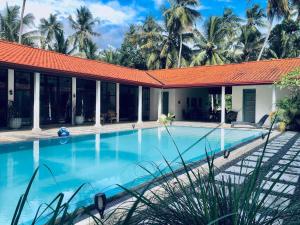 a swimming pool in front of a house with palm trees at Villa Blue Lotus Katunayake in Katunayake +22 photos