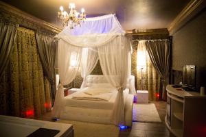 een slaapkamer met een wit hemelbed en een kroonluchter bij Hotel Boutique Mikaela (Adult Only) in Braşov