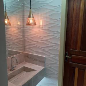 a bathroom with a sink and two lights at Casa de Temporada com Piscina in Serra