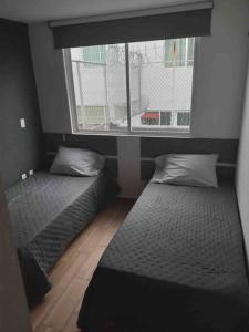 twee bedden in een kamer met een raam bij Casa entera Morelia, hospitales, corporativos 1 in Atapaneo