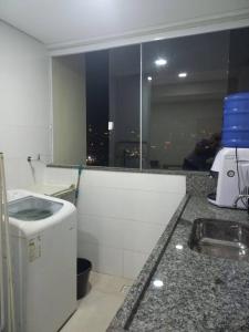 uma cozinha branca com um lavatório e uma janela em Apt aconchegante com 2 quartos! j em Patos de Minas