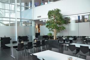 ein Restaurant mit Tischen, Stühlen und einem Baum in der Unterkunft Hotel DGI-Huset Herning in Herning