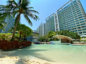 a swimming pool with a palm tree and buildings at Azure Staycation in Manila