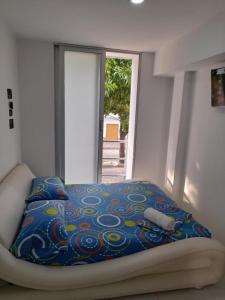 a bed with a blue blanket and a window at Hotel URUMITA MAGICA in Valledupar
