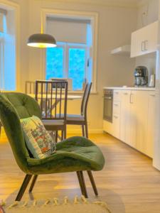sala de estar con silla verde y cocina en Enjoy Reykjavík Yellow Door Apartment, en Reikiavik