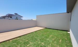 a backyard with a white fence and grass at Casa Mar Dom Pedro in Arroio do Sal