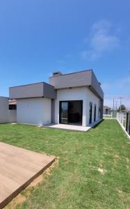 a large white house with a grass yard at Casa Mar Dom Pedro in Arroio do Sal
