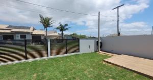 a backyard with a white fence and grass at Casa Mar Dom Pedro in Arroio do Sal