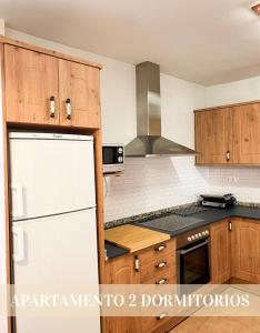 uma cozinha com um frigorífico branco e armários de madeira em Alojamientos Apolonia, La Fresneda em La Fresneda