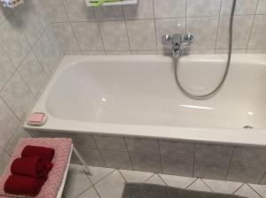 una vasca da bagno bianca con rubinetto e asciugamani rossi di Rote Etage Pension mit Balkon, 4 km von Kitzingen nur 16 km von Würzburg! a Mainstockheim