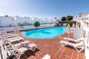 een zwembad op het dak van een hotel met ligstoelen bij Casa Lina HolidayFV in Corralejo