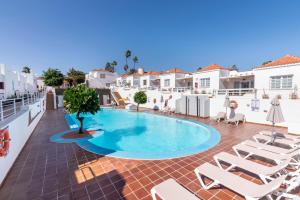 een zwembad met ligstoelen op een patio bij Casa Lina HolidayFV in Corralejo