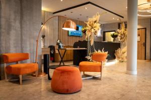 a salon with orange chairs and a table and a mirror at Kyriad Chartres in Chartres