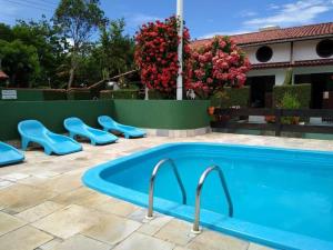 una piscina con asientos azules junto a una casa en Condomínio Vila Gustavo -excelente localização, en Caraguatatuba