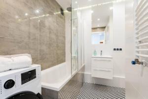 a bathroom with a shower and a tub and a sink at Sandstone Apartment Targowek in Warsaw