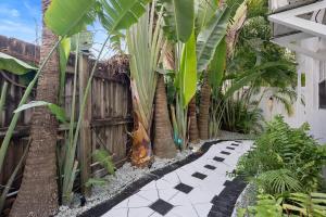 einen Garten mit einem schwarz-weiß karierten Gehweg in der Unterkunft Las Olas Guest House in Fort Lauderdale