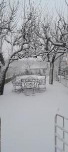 a table and benches covered in snow next to trees at Kristina Mitllari 1 in Pogradec