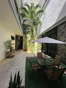 a patio with a table with chairs and an umbrella at Hotel Boutique Murana Tulum in Tulum