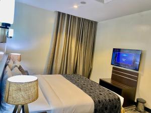 a hotel room with a bed and a flat screen tv at Golden Tulip Oniru Suites in Lagos