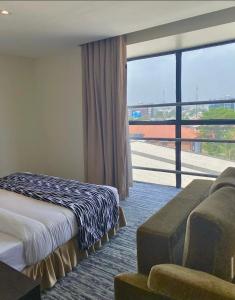 a hotel room with a bed and a couch and a large window at Golden Tulip Oniru Suites in Lagos