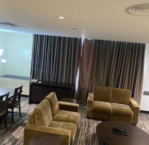 a living room with a couch and chairs and a piano at Golden Tulip Oniru Suites in Lagos