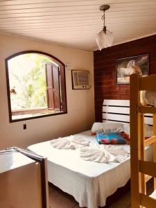 a bedroom with a large bed with a window at Pousada Suites Praia de Costazul in Rio das Ostras