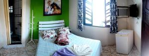 a green room with a bed with pillows on it at Pousada Suites Praia de Costazul in Rio das Ostras