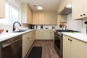 uma cozinha com armários brancos e electrodomésticos pretos em Stylish Apartment Near DTLA em Los Angeles