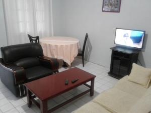 uma sala de estar com um sofá e uma cadeira e uma televisão em Residence Saint-Jacques Centre Ville Pointe Noire em Pointe-Noire