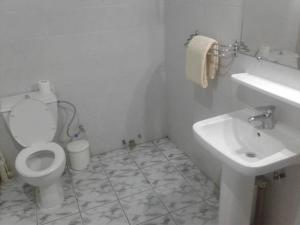 a white bathroom with a toilet and a sink at Residence Saint-Jacques Centre Ville Pointe Noire in Pointe-Noire