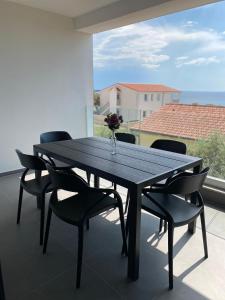 a table with chairs and a vase of flowers on a balcony at Lili Rose Mandre Luxury Apartments in Mandre