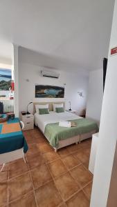 a white bedroom with a bed and a table at Caminhos nos Levam pela Ilha in Ponta Delgada
