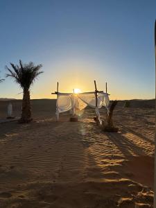 a boat on the beach with the sunset in the background at Sahara Luxury Camp VIP in Merzouga