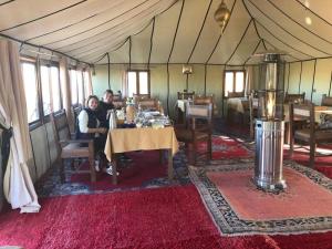 un groupe de personnes assises à une table dans une tente dans l'établissement Sahara Luxury Camp VIP, à Merzouga