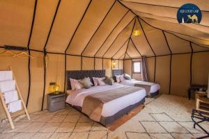 - une chambre avec 2 lits dans une tente dans l'établissement Sahara Luxury Camp VIP, à Merzouga