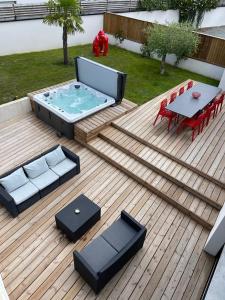 een terras met een hot tub en een tafel en stoelen bij Résidence Tamaris Loft House in La Mézière