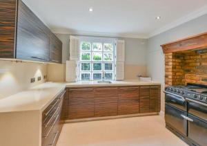 a large kitchen with wooden cabinets and a window at FAIRYTALE BELGRAVIA HOUSE - 2 beds 2 baths 4 people in London