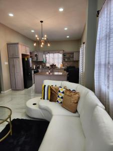 a living room with a white couch and a kitchen at Malik SuitesGY 