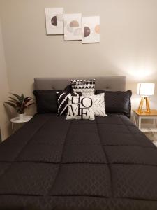 een bed met een zwart dekbed in een slaapkamer bij Malik SuitesGY 