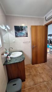 a bathroom with a sink and a wooden door at Caminhos nos Levam pela Ilha in Ponta Delgada