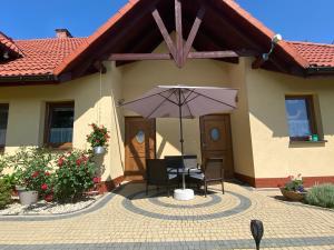 une terrasse avec une table et un parasol en face d'une maison dans l'établissement Apartament Zacisze, à Ustroń