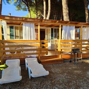 une grande maison en bois avec 2 chaises et un grill dans l'établissement International Holidays Luxe House Pool Beach-Lerici-Cinque Terre-Liguria Case Vacanze in Touristic Village River, à Ameglia