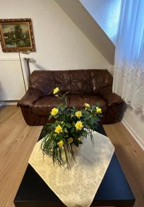 sala de estar con sofá y mesa con flores amarillas en City Wohnung 12, en Brühl