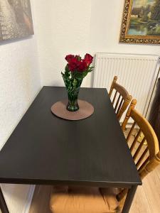 a black table with a vase with red roses on it at City Wohnung 12 in Brühl