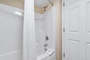 a bathroom with a shower with a white shower curtain at Kelleys Island Venture Resort in Kelleys Island