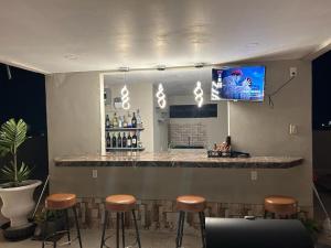a bar with stools and a tv on the wall at Malik SuitesGY in Nismes